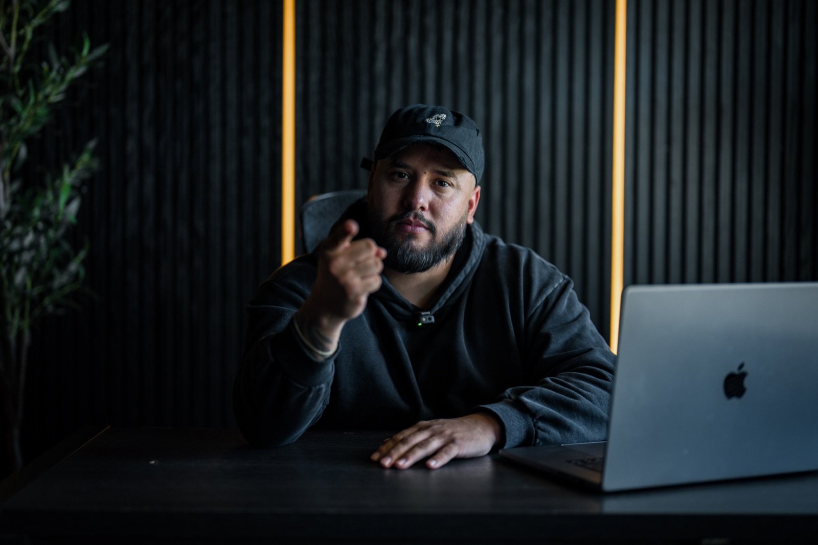 Kevin Romero pointing toward the camera at his desk in his Riverside office