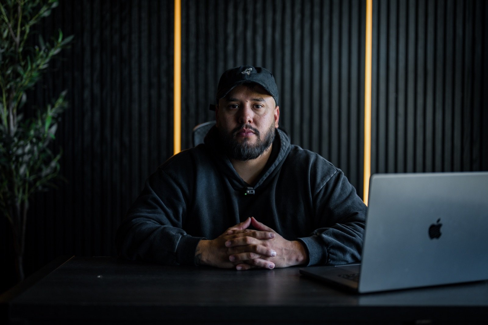 Kevin Romero seated at his desk with hands folded, in a calm portrait
