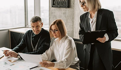Three professionals analyzing documents in a modern office setting, focusing on credit reports and financial strategies.