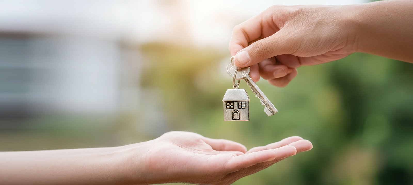 Person handing over house keys to another individual, symbolizing home ownership and financial empowerment related to credit repair services.